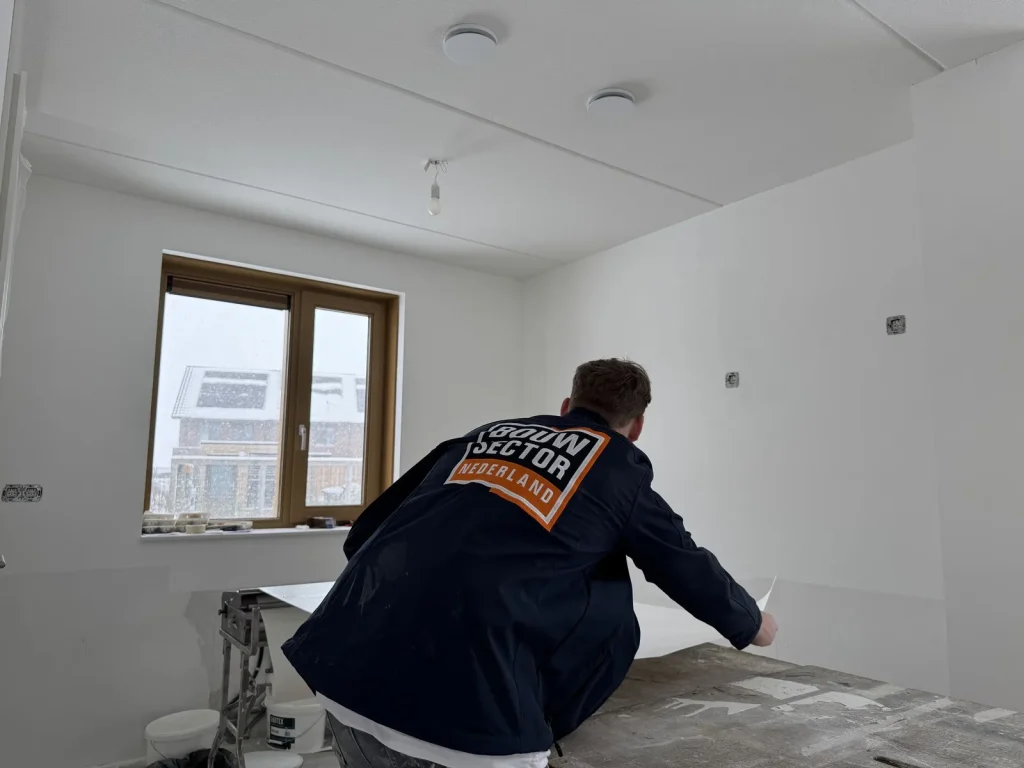 Behanger van Bouwsector Nederland pakt een baan vlies van de plaktafel in een nieuwbouwkamer